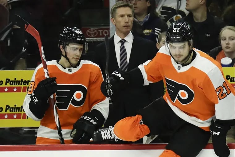Flyers Head Coach Dave Hakstol watches his team next to center Travis Konecny and center Scott Laughton leaping on the ice against the St. Louis Blues on Saturday, January 6, 2018 in Philadelphia.