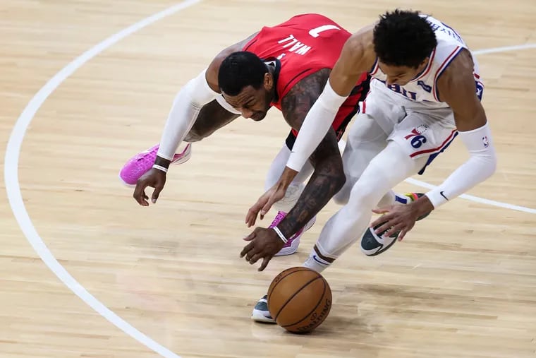 Matisse Thybulle (right) and John Wall battle for the loose ball during the fourth quarter of Wednesday's win against the Rockets.