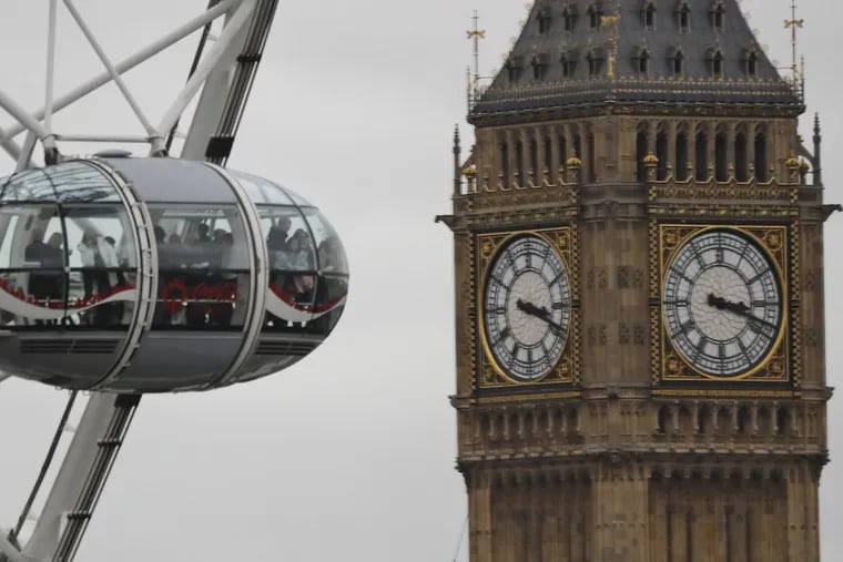Visitors enjoy the London Eye ride beside The Elizabeth Tower housing the Big Ben bell on a cloudy day in London.