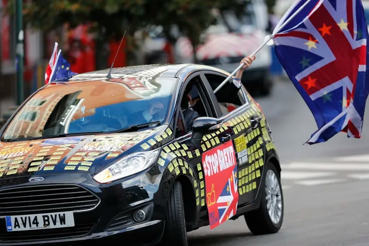 A man waves an E.U. and British flag out of a car adorned with anti-Brexit decals in front of E.U. headquarters in Brussels on Thursday.