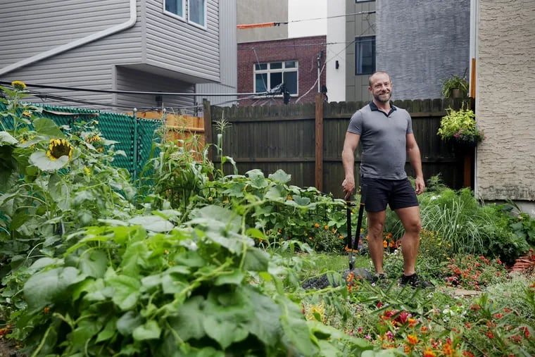 Antonio Luis, a physician who was hospitalized with COVID-19, stands in the neighborhood garden that he and his partner, Salim Rouwayheb, and their roommate, Matt Richards, helped create in an empty lot in Philadelphia's Point Breeze section.