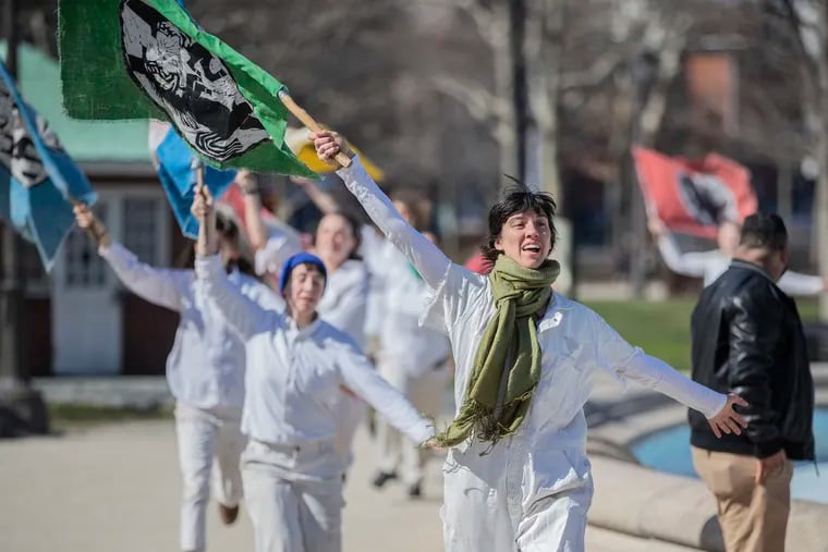 Members of Bread and Puppet Theatre run around the Swan Fountain at Logan Circle as part of their performance during Philadelphia's celebration of International Women's Day on Sunday.