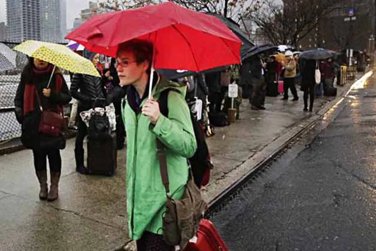 Passengers wait for a BoltBus to arrive during a light rain, Wednesday, Nov. 27, 2013 in New York.  Some unusually warm December temperatures are on tap for Philadelphia over the next few days. (AP Photo/Mark Lennihan/File)