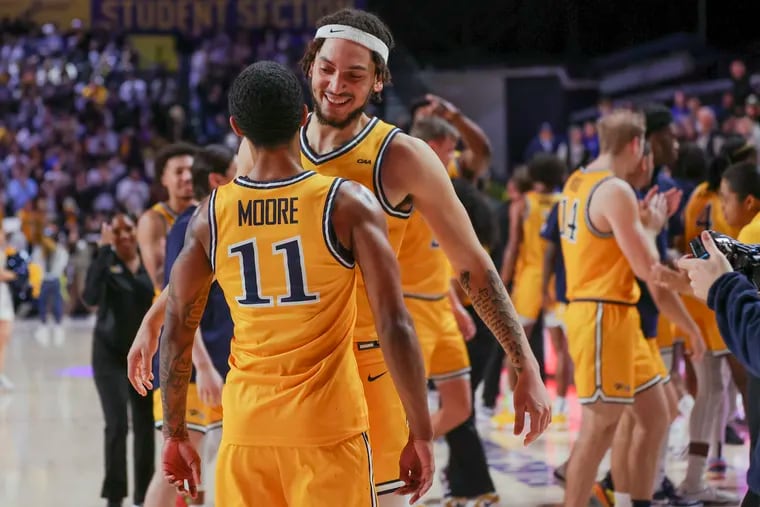 Drexel forward Garfield Turner celebrates with Justin Moore after a win over Delaware on Saturday. Moore led the Dragons with 18 points.