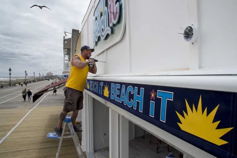 Dan Pitcherello works on the outdoor lights at Ocean City’s Beach It boutique on Wednesday. Businesses up and down the Ocean City boardwalk are finalizing preparations for the start of the summer season.