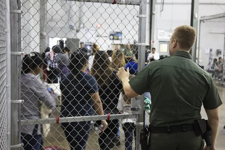 In this photo provided by U.S. Customs and Border Protection, a U.S. Border Patrol agent watches as people who have been taken into custody related to cases of illegal entry into the United States, stand in line at a facility in McAllen, Texas, Sunday, June 17, 2018.