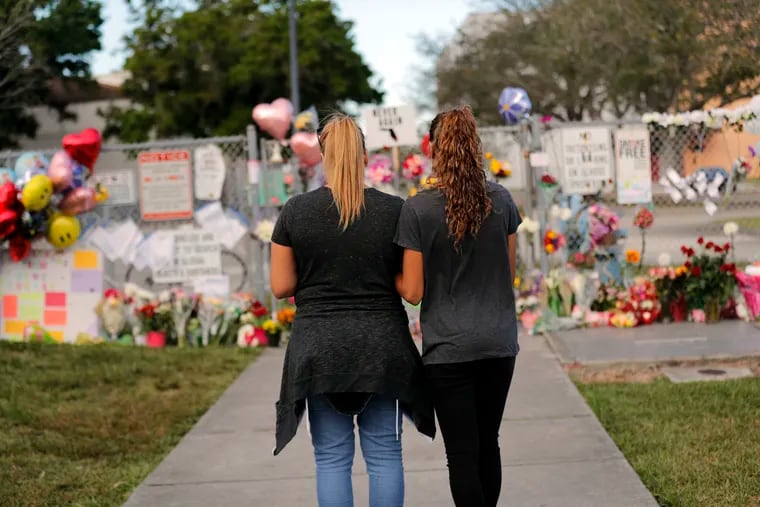 Sara Smith (left) and her daughter Karina Smith visit a makeshift memorial last February outside Marjory Stoneman Douglas High School, where 17 students and faculty were killed in a mass shooting.
