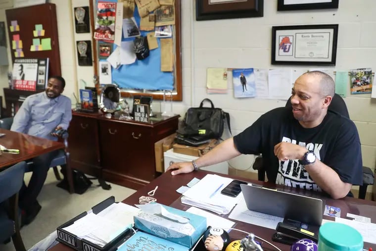 Richard Gordon, principal of Paul Robeson High School in West Philadelphia, laughs at his desk in his office after giving student Saniah Aaron a new laptop for remote learning on Sept. 29, 2020. Gordon was named Principal of the Year by the National Association of Secondary School Principals on Tuesday.