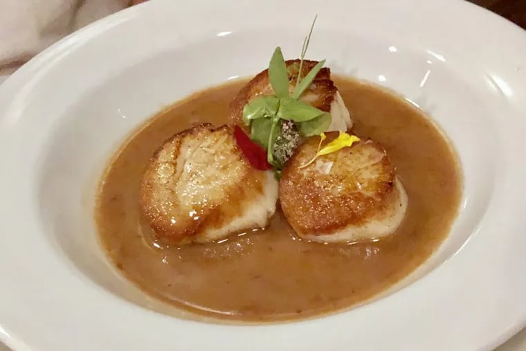 Seared scallops are served at Monk’s Cafe with a tangy butter made from Flemish sour ale.