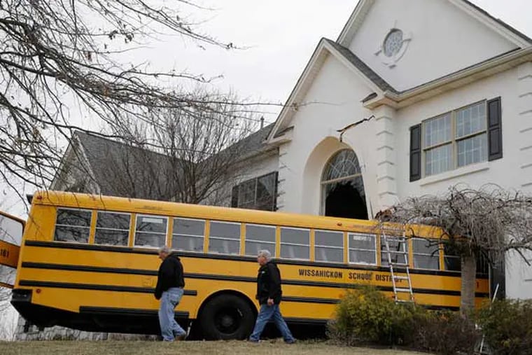 People inspect a school bus that crashed into a home Tuesday morning, March 24, 2015, in Montgomery County. (AP Photo/Matt Rourke)