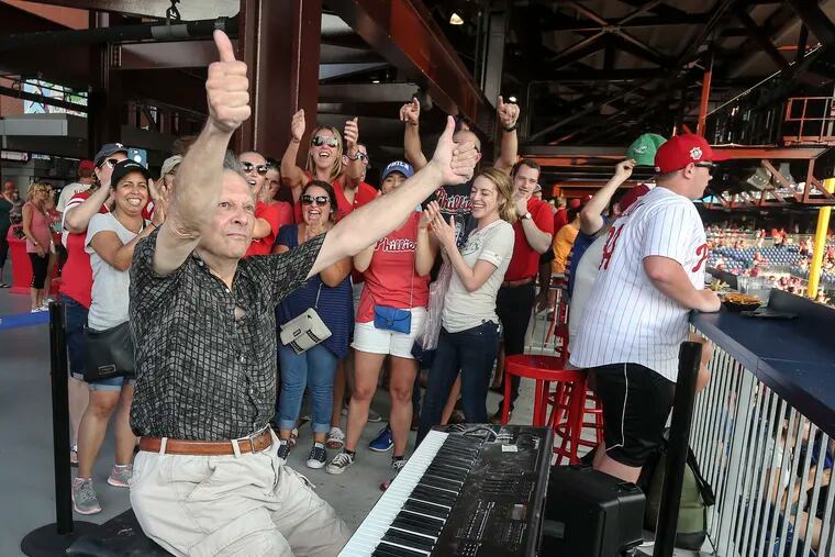The organist George Akerley responds to the crowd at Citizens Bank Park after playing a triumphant version of "Take Me Out to the Ball Game" during "Throwback Thursday" at a Phillies doubleheader last week.
