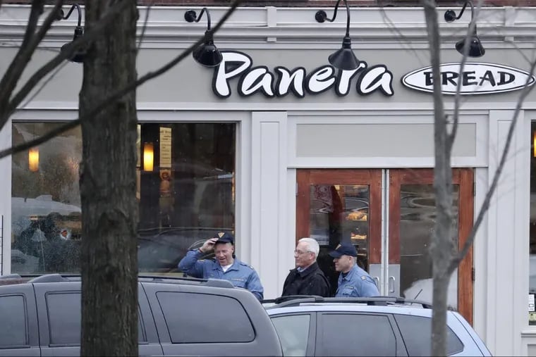 A hole is seen on the glass panel, far left, as New Jersey State Police officials walk out of a Panera Bread restaurant in Princeton, N.J., where an armed man was holed up across the street from Princeton University on Tuesday.