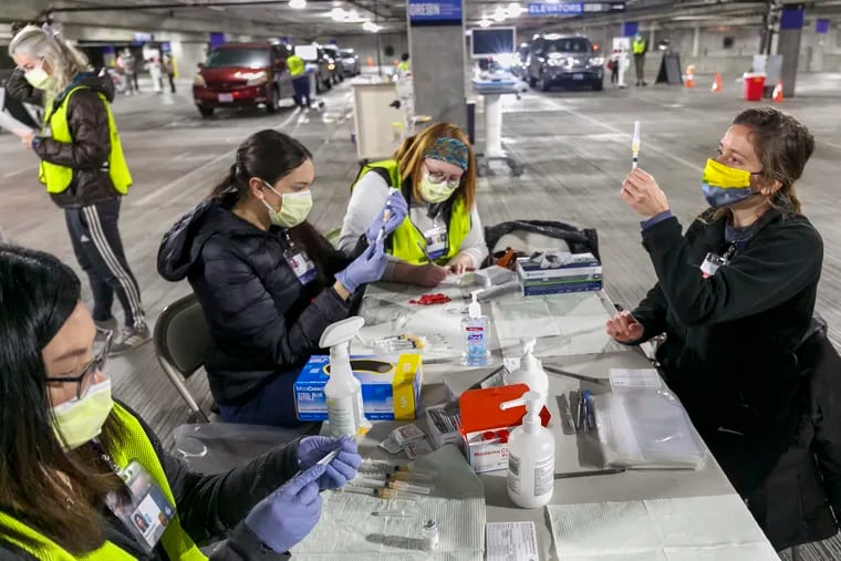 Medical professionals from Oregon Health & Science University load syringes with the Moderna COVID-19 vaccine at a drive-thru vaccination clinic in Portland, Ore.