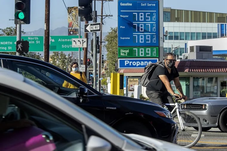 A bicycle rider maneuvers around motorists stuck in traffic in downtown Los Angeles on Friday, where the price of gasoline approaches close to $8 a gallon.