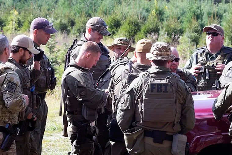 FBI agents gather for a briefing in a field during the continued search for Eric Frein on Wednesday, Oct. 8, 2014. ( ED HILLE / Staff Photographer )