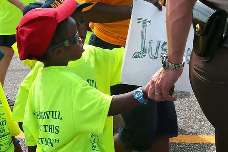 St. Louis County Police Sgt. Colby Dolly joins hands with five-year-old Zion King Frenchie during a march with members of the St. Louis chapters of the NAACP and the National Urban League on West Florissant Avenue in Ferguson, Mo., on Saturday, Aug. 23, 2014. Ferguson's streets remained peaceful as tensions between police and protesters continued to subside after nights of violence and unrest that erupted when Officer Darren Wilson, a white police officer, fatally shot Michael Brown, an unarmed black 18-year-old. (AP Photo/St. Louis Post-Dispatch, Robert Cohen)
