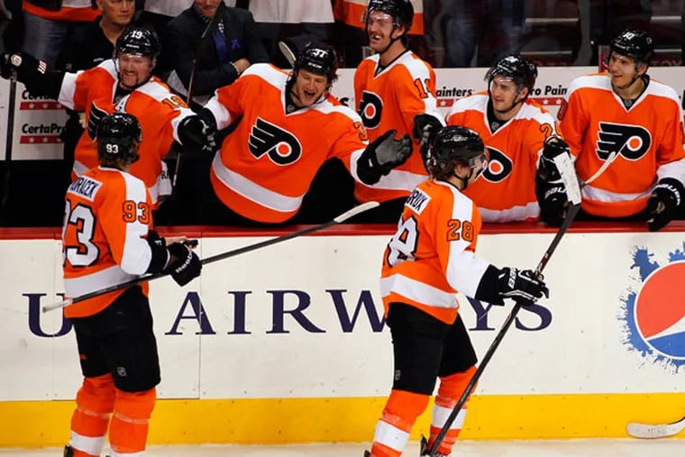 Claude Giroux, right, who scored his first goal of the season, is followed by Jakub Voracek, who got the assist, as they skate past their teammates on the bench during the third period of an NHL hockey game with the Edmonton Oilers, Saturday, Nov. 9, 2013, in Philadelphia. The Flyers won 4-2. (Tom Mihalek/AP)
