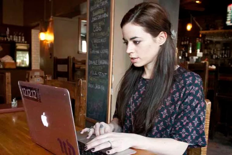 Jessica Mellen, co-owner of the Falls Taproom on  Midvale Ave, uses her computer and IPhone to shop online. ( RON TARVER / Staff Photographer ) December 12, 2013