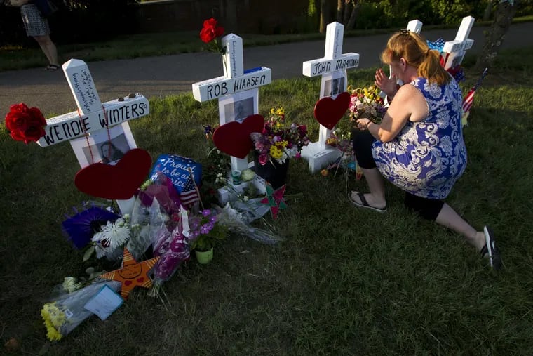 Colleen Joseph prays over the crosses at a makeshift memorial at the scene outside the office building housing The Capital Gazette newspaper in Annapolis, Md., on Sunday, July 1, 2018. Jarrod Ramos is charged with murder after police say he opened fire Thursday at the newspaper.