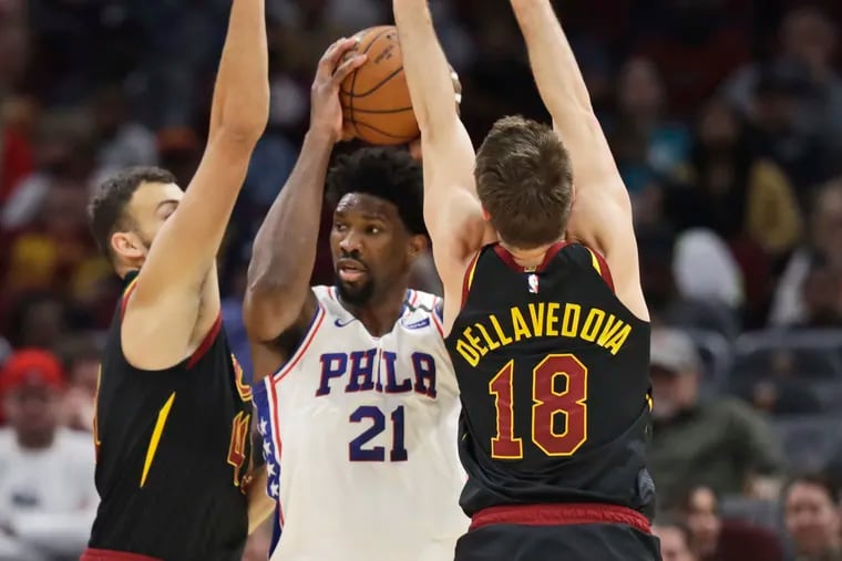 Sixers Joel Embiid squeezes between Cleveland Cavaliers' Ante Zizic and Matthew Dellavedova in the first quarter. Embiid suffered a game-ending shoulder injury late in the quarter.