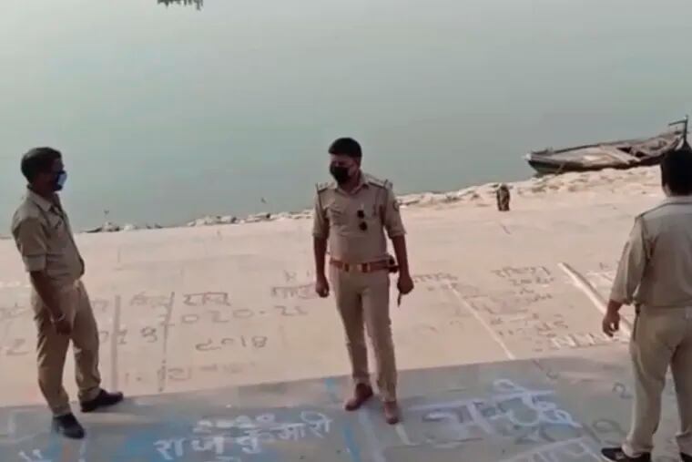 This frame grab from video provided by KK Productions shows police officials on Tuesday standing guard at the banks of the Ganges River where several bodies were found.
