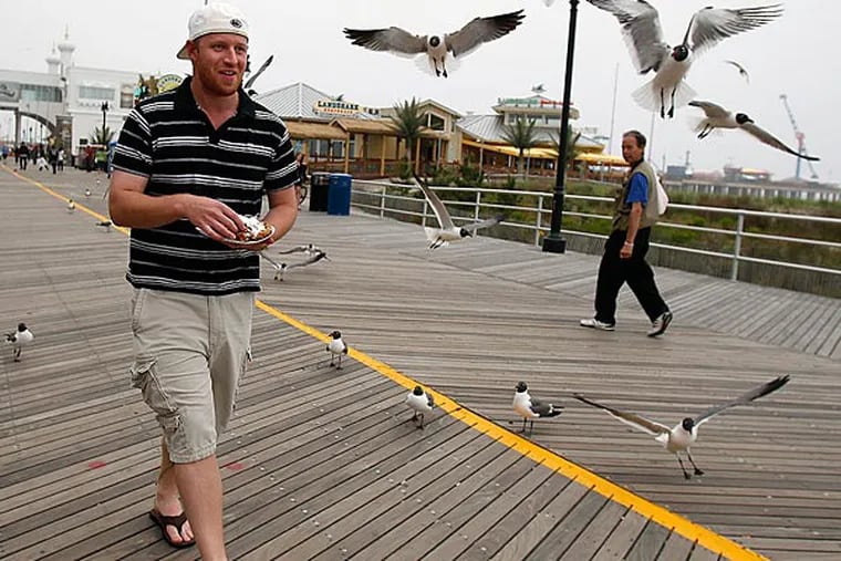 Jeff Thompson, of York, Pa., is followed by a flock of seagulls as he tries to eat funnel cake on the boardwalk in Atlantic City, NJ on May 23, 2013.  ( DAVID MAIALETTI / Staff Photographer )