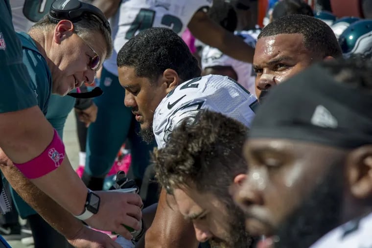 Eagles offensive line coach Jeff Stoutland (left) speaks with rookie right tackle Halapoulivaati Vaitai on the bench after the rookie gave up a sack of Carson Wentz in the game Oct. 16, 2016 in Washington.  Washington won 27-20.