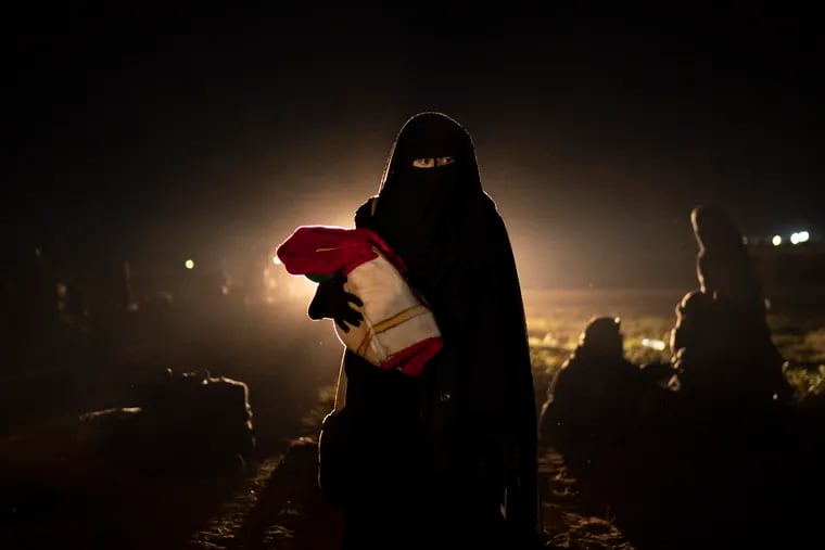 A woman who was evacuated out of the last territory held by Islamic State militants holds her baby after being screened by U.S.-backed Syrian Democratic Forces (SDF) in the desert outside Baghouz, Syria, Monday, Feb. 25, 2019. (AP Photo/Felipe Dana)