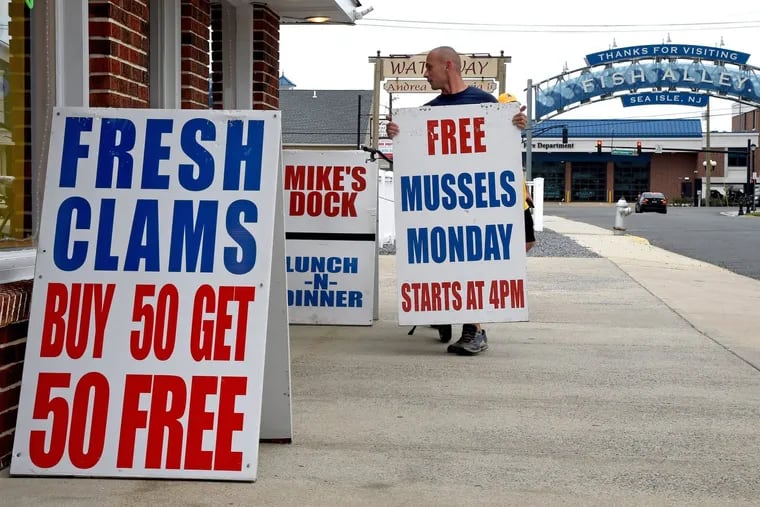Marek Bijok moves the signs around in front of Mike's Seafood in Sea Isle City. "Did I lose money? Yeah," owner Mike Monichetti said Monday. "Did I feel good doing it? Yeah."