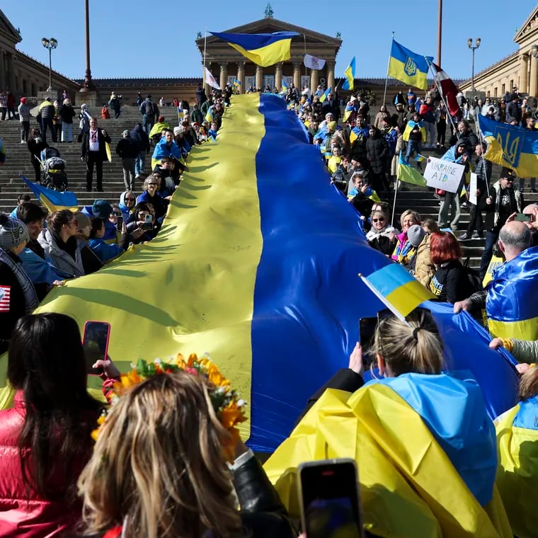 People unfurl a 60-meter-long Ukrainian flag during a rally on the Art Museum steps to mark the second anniversary of Russia’s invasion of Ukraine, in Philadelphia, Pa. on Sunday. After a series of speakers, the crowd marched along the Parkway and then onto Independence Mall.