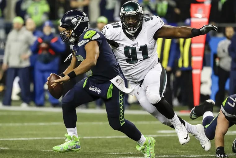 Seattle Seahawks quarterback Russell Wilson runs past Eagles defensive tackle Fletcher Cox in the fourth-quarter on Sunday, December 3, 2017 at CenturyLink Field in Seattle. YONG KIM / Staff Photographer