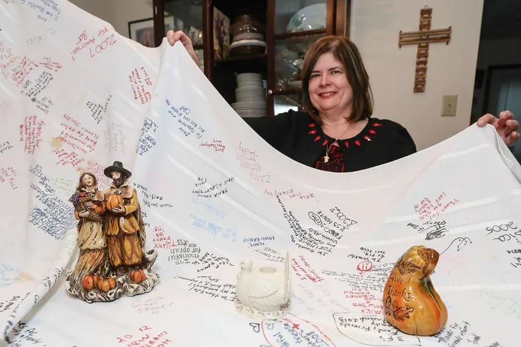 Pat Quigley shows a previous polyester tablecloth with notes from family members gathered for the holidays. Other families have similar traditions, though it is difficult to determine the source of the idea.