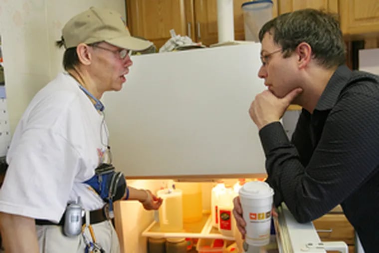 Russell Kidd ( left) and Robert Slack (right), a caseworker with the ARC (Association for Retarded Citizens) of Philadelphia, discuss the best way to reorganize the refrigerator in Kidd&#0039;s Olney home.