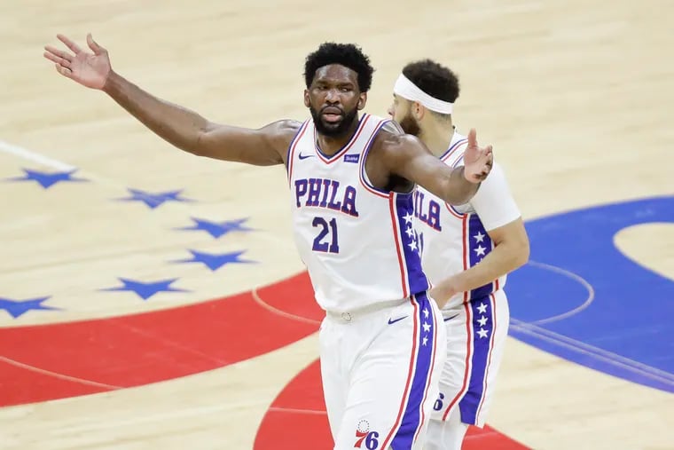 Sixers center Joel Embiid raises his arms in front of teammate Seth Curry on Sunday in Game 7 against the Atlanta Hawks.