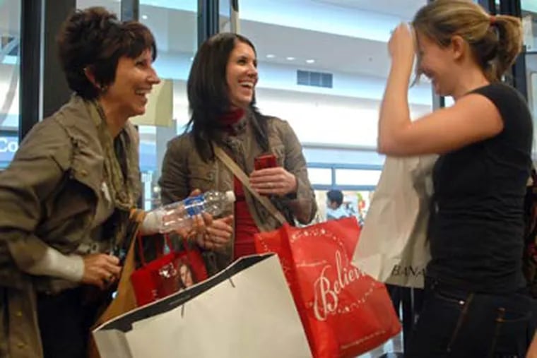 Seasoned Black Friday shopper Danielle Verdes of Haverford, center, hooks up with her cousin Megan Charitonchick, right, as she shops with her mother Joyce McQuaid, left, in the Banana Republic store at the Court at the King of Prussia Mall. Megan stood in line while Danielle and her mother shopped, bringing Megan items to buy as they found them. (Tom Gralish / Staff Photographer)