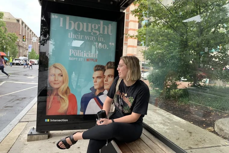 Penn student Melina Lawrence waits in one of the city's new bus shelters at 34th and Walnut Streets, which vandals damaged earlier this year.