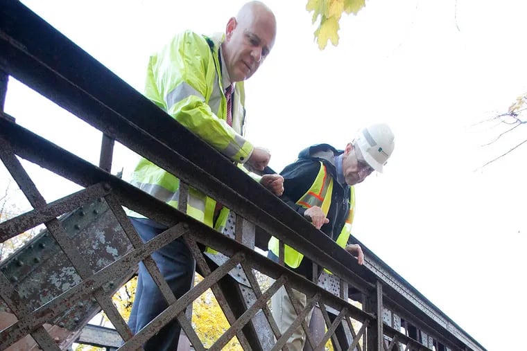 Jeffrey Knueppel, SEPTA Deputy General Manager Operations/EM&C Divisions, (left) and Lester Toaso, PENDOT District Executive Engineering District 6-o, (right) on the North Main St. bridge over Septa, exposed steel truss members along Main St. are experiencing extensive deterioration and corrosion. Also concrete that encapsulates the steel beams below the deck are deteriorated and corroded steel is exposed. This is a steel truss bridge on N. Main St. in Sellersville on November 7, 2013.  ( ELIZABETH ROBERTSON / Staff Photographer )