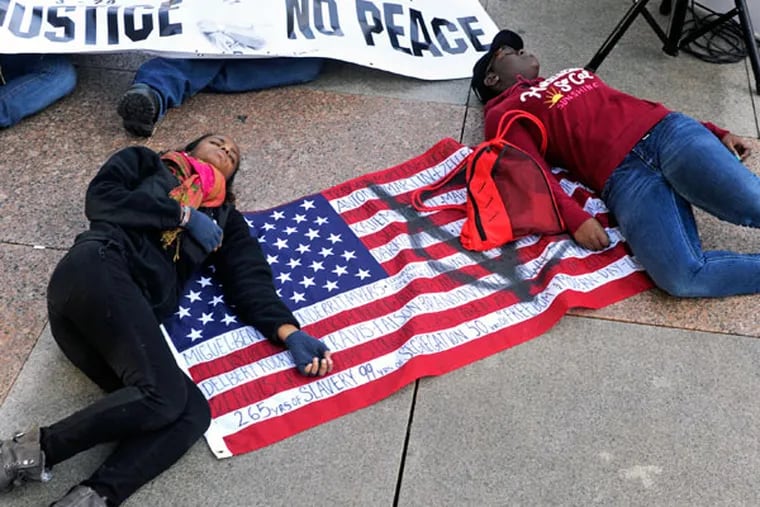 Jordan Jackson (left), 19, of Coatesville and Justus Parker (right), 18, of Downingtown participate in the "die in" organized by Muslims Mobilized Against Police Brutality on Dec. 27, 2014, following a rally and march on Thomas Paine Plaza at the Municipal Services Building. ( TOM GRALISH / Staff Photographer )