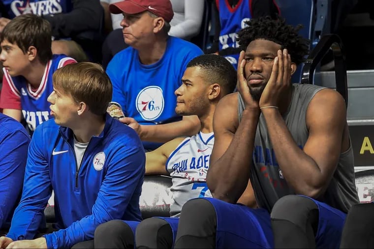 Joel Embiid (right) watches Sunday’s Sixers scrimmage from the bench.