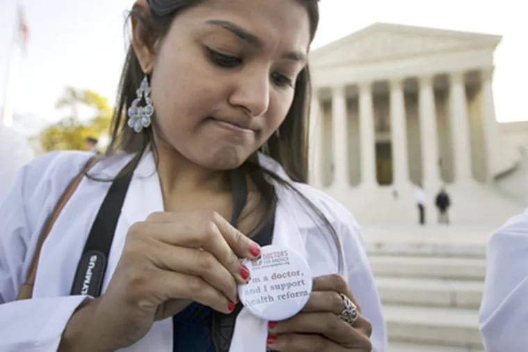 Dr. Sonia Nagda puts on a pin supporting the health care reform law
signed by President Obama as she gathers with other health care
professionals in front of the Supreme Court in Washington, Monday,
March 26, 2012, as the court begins three days of arguments on the
health care. (AP Photo/Charles Dharapak)