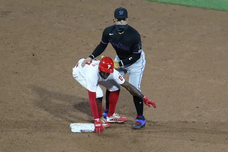 Roman Quinn (left) of the Phillies and Isan Díaz of the Marlins look toward first base as the Marlins complete a double play on Friday.