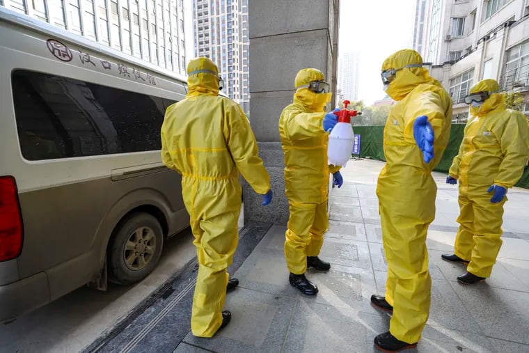 Funeral workers disinfect themselves after handling a virus victim in Wuhan in central China's Hubei Province, Thursday, Jan. 30, 2020. China counted 170 deaths from a new virus Thursday and more countries reported infections, including some spread locally, as foreign evacuees from China's worst-hit region returned home to medical observation and even isolation.
