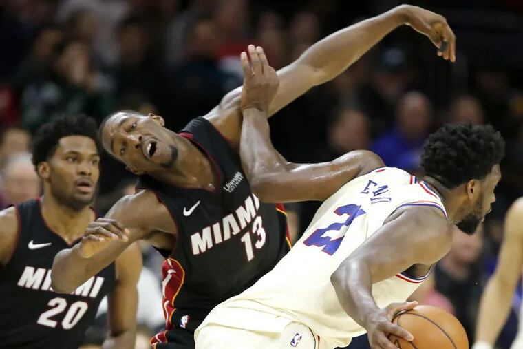 Joel Embiid, right, of the Sixers is called for an offensive foul and he throws his arm into Bam Adebayo, center, of the Heat during the 4th quarter of their game at the Wells Fargo Center on Feb. 2, 2018.