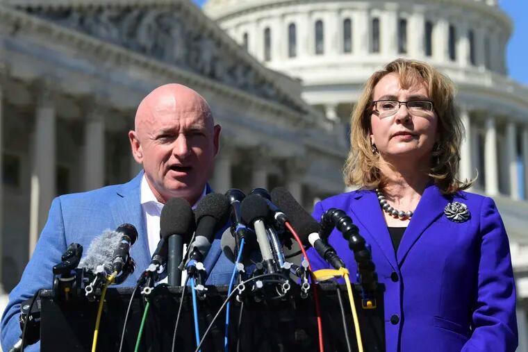 FILE- In this Oct. 2, 2017, file photo former Rep. Gabrielle Giffords, D-Ariz., right, listens as her husband Mark Kelly, left, speaks on Capitol Hill in Washington. Kelly is kicking off his U.S. Senate campaign Saturday, Feb. 23, 2019, with a rally in Tucson.