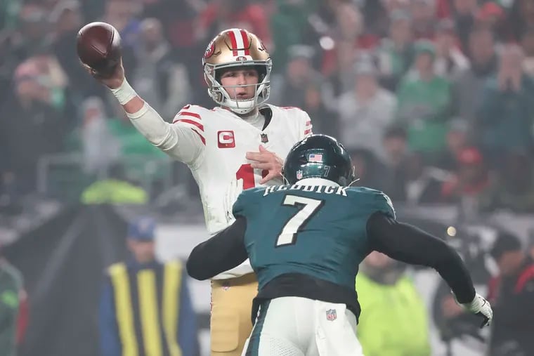 San Francisco 49ers quarterback Brock Purdy throws the football as Eagles linebacker Haason Reddick closes in.