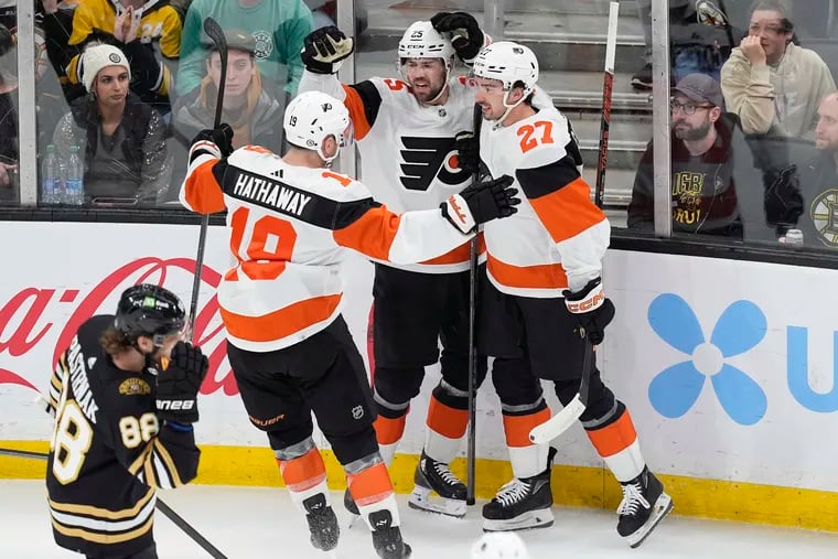The Flyers' Ryan Poehling celebrates his goal with Garnet Hathaway and Noah Cates (27) in front of Boston's David Pastrnak during the first period Saturday.