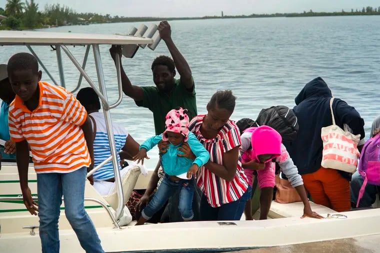 A woman carries a girl in her arms after being evacuated from a nearby Cay due to the danger of floods after arrive on a ship at the port before the arrival of Hurricane Dorian in Sweeting's Cay, Grand Bahama, Bahamas, Saturday Aug. 31, 2019.   Dorian bore down on the Bahamas as a fierce Category 4 storm Saturday, with new projections showing it curving upward enough to potentially spare Florida a direct hit but still threatening parts of the Southeast U.S. with powerful winds and rising ocean water that causes what can be deadly flooding.