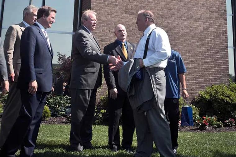 Robert M. Damminger, Gloucester County Freeholder Director, (left) shakes hands with New Jersey Senate President Stephen Sweeney as other officials stand by after the unveiling of the new Rowan College At Gloucester County logo on the Eugene J. McCaffrey College Center of the college. ( RON TARVER / Staff Photographer ) July 01 2014