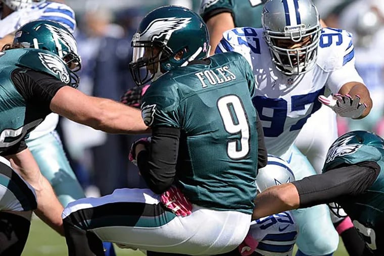 Eagles quarterback Nick Foles is sacked by Dallas Cowboys defensive end George Selvie (99) as defensive tackle Jason Hatcher (97) helps during the first half. (Michael Perez/AP)