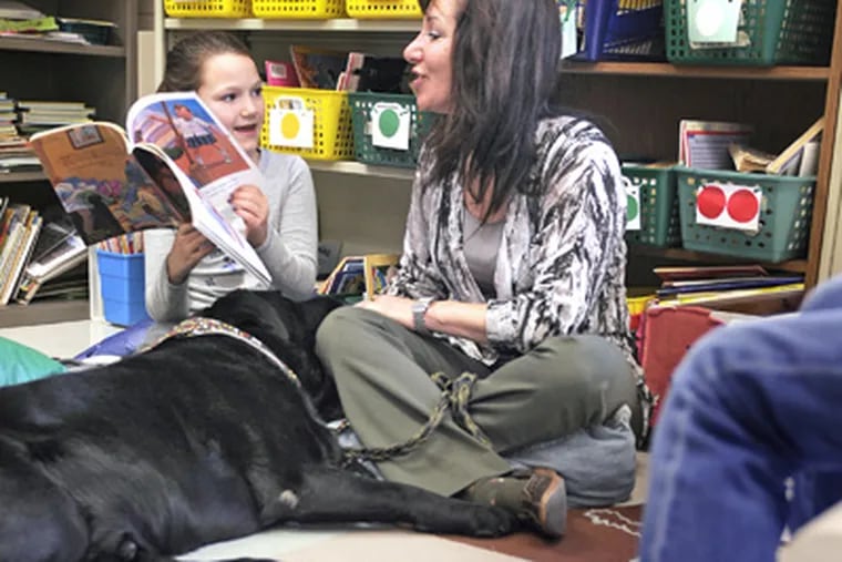 Maggie Burke, 8, reads to Wendi Huttner and a Lab named Wes in Richboro. Huttner's program helps youngsters overcome anxiety by reading to dogs. (Tom Gralish / Staff Photographer)